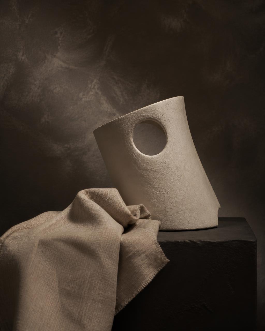 Ivory sculpture and raw textile in warm gallery light