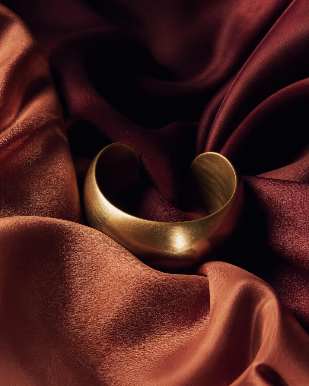 Brass jewelry in folds of terracotta silk